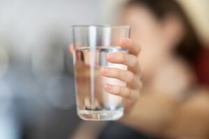 Person holding glass of water purified by a reverse osmosis water filter. 