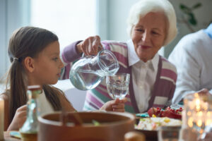 Grandmother pouring her granddaughter water treated with Brita PRO water filtration systems. 